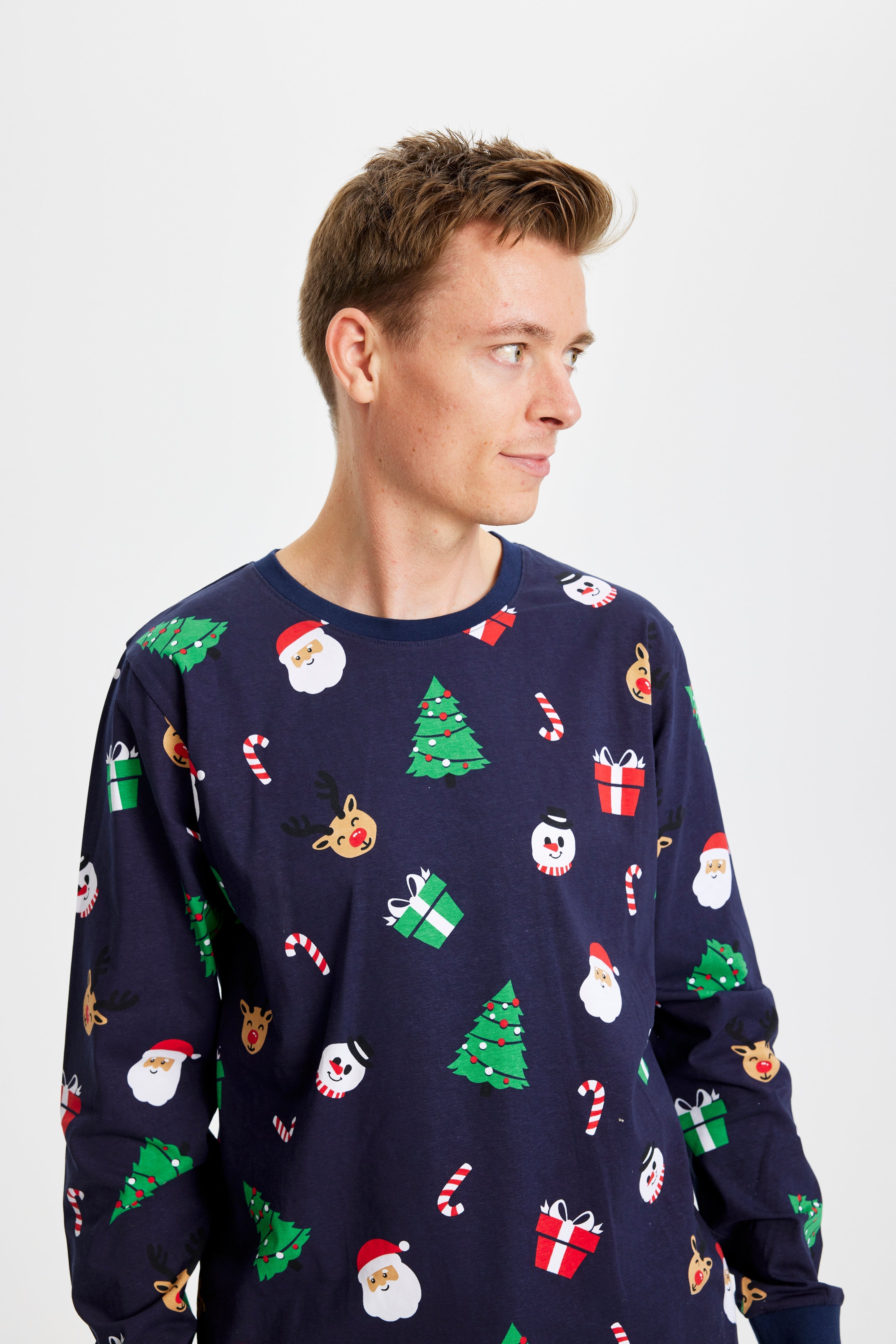 Eine aufgeregte Frau mit einem Geschenk in einem blauen Weihnachtspyjama mit Weihnachtsbäumen.